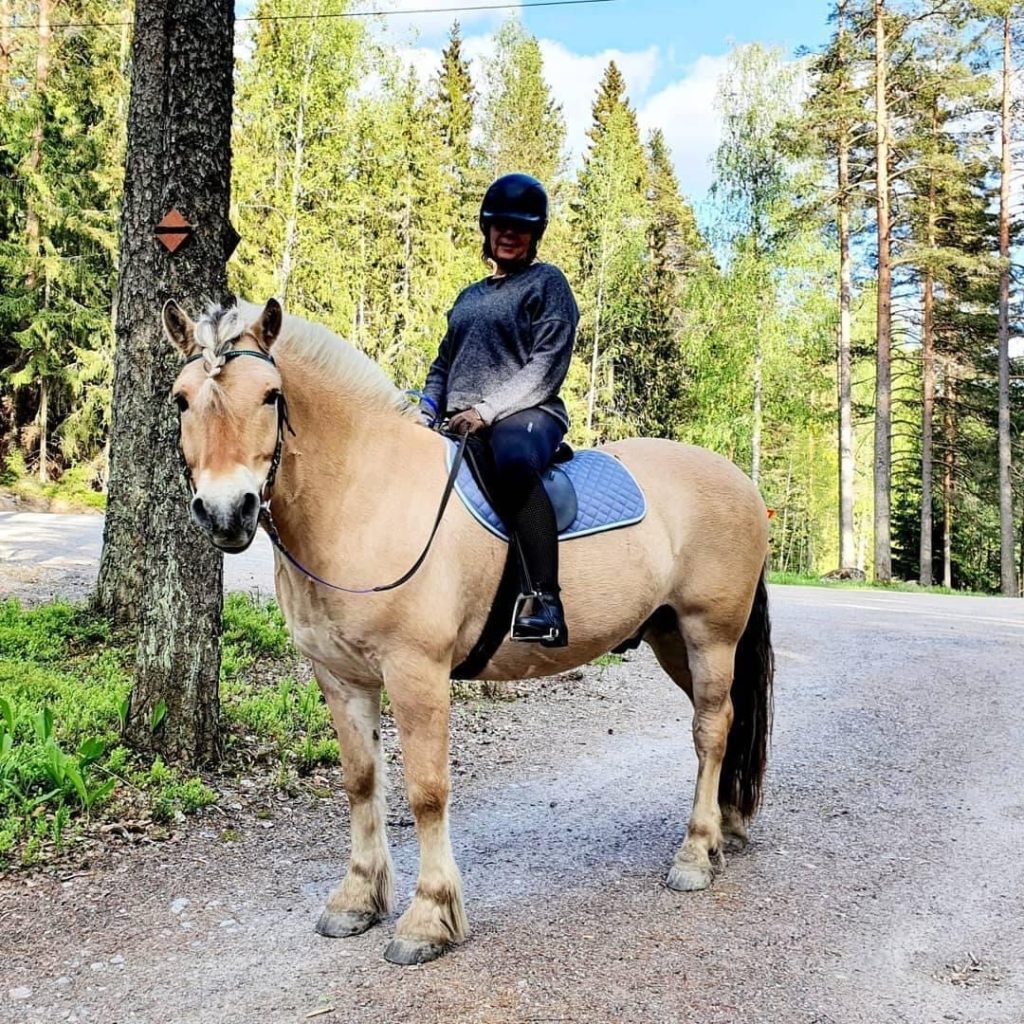 Nainen istuu Vuononhevosen selässä.